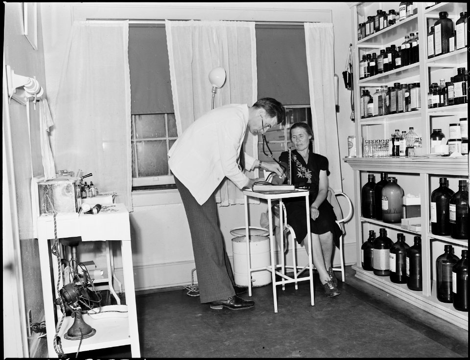 Doctor taking blood pressure of miner's wife in treatment room of clinic. Inland Steel Company Wheelwright ^1 & 2... - NARA - 541471