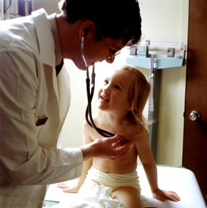 Doctor uses a stethoscope to examine a young patient photo