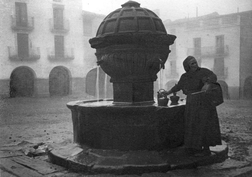 Dona agafant aigua de la font de la plaça de Prades