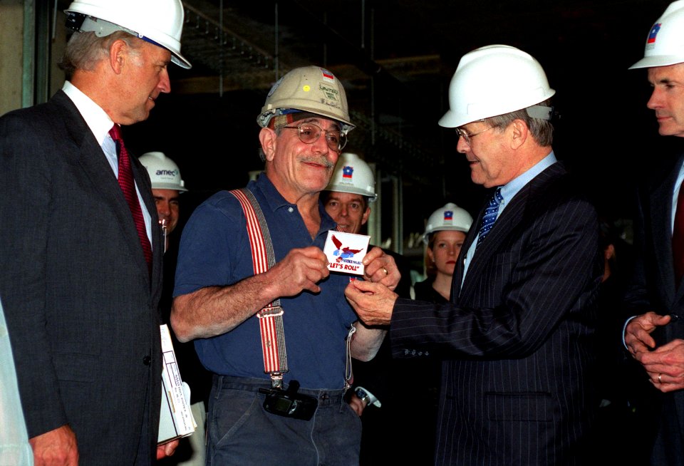 Donald Rumsfeld presents a decal to sheet metal worker Michael Flocco