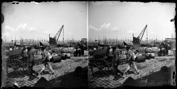 Dos homes , un carro i botes en un moll del port de Barcelona