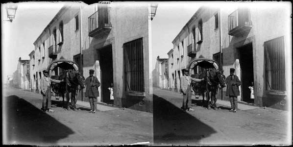 Dos homes amb un carro tirat per un cavall en un carrer del poble