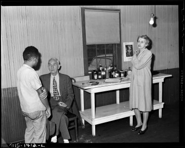 Dr. and Mrs. Rucker and patient, Dr. Rucker is partially paralized and Mrs. Rucker does much of the work under his... - NARA - 540787
