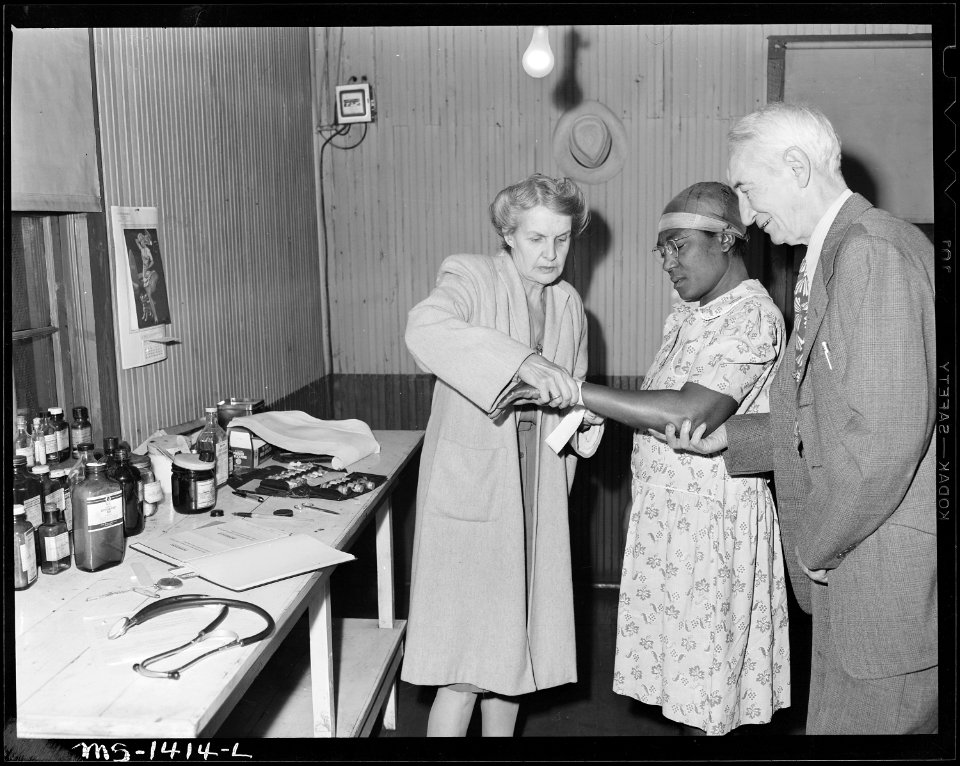 Dr. and Mrs. Rucker strap up sprained wrist of miner's wife. Equipment and supplies in this office permit only minor... - NARA - 540789