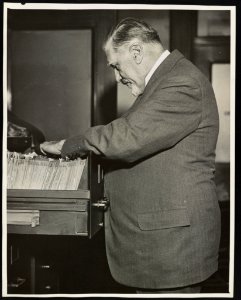 Dr. Charles Norris, New York City's first chief medical examiner, looking in file cabinet LCCN2013650280 photo