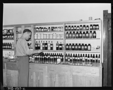 Dr. R.V. Toker prepares prescription of a patient. All drugs prescribed at this clinic are included in the regular... - NARA - 540833