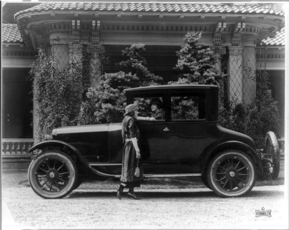 Driver's side view of 1920 Chandler, with a woman standing at the door talking to another woman seated inside) - photo by C.M. Black LCCN95500764