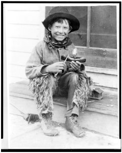 Eagle Aims Back, Indian boy, of the Glacier National Park Reservation, carving a toy canoe with a jack knife LCCN93500319