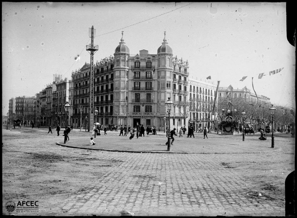 Gent passejant i nens jugant a la plaça Joan Carles I, cruïlla entre l'avinguda Diagonal i el passeig de Gràcia de Barcelona