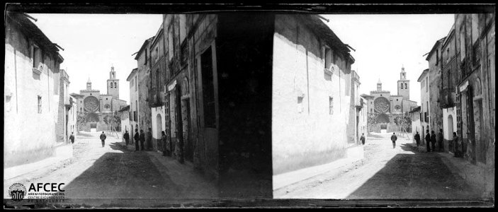 Gent en un carrer de Sant Cugat . Al fons, la façana del Monestir de Sant Cugat del Vallès