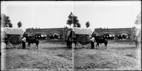 Gent i carros a la riera , als afores de Cardedeu i al fons un pont