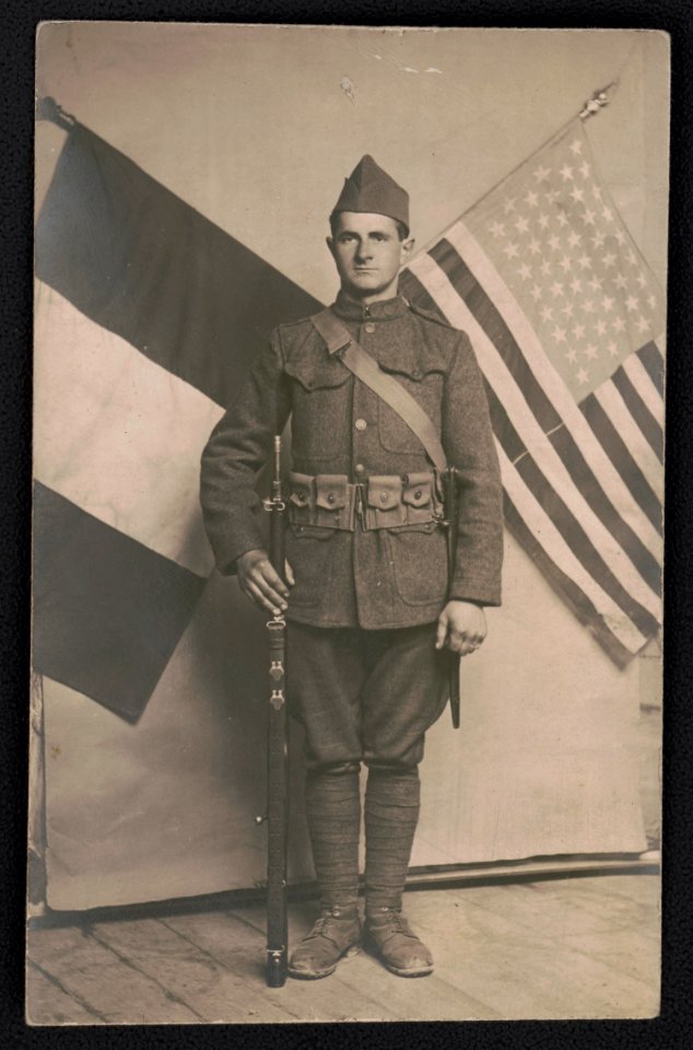 George Hasken in uniform with rifle in front of French and American flags LCCN2018645965