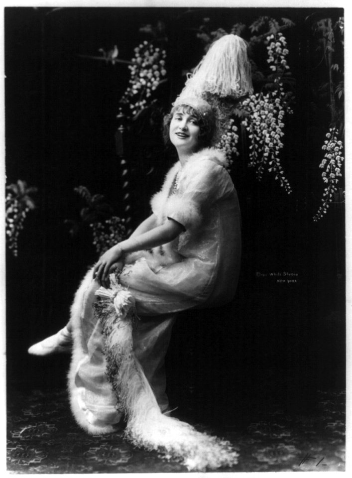 Gaby Deslys, 1884-1920, full length portrait, seated, facing slightly left in ornate hat and dress LCCN2005693311