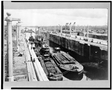 Gatun locks looking toward Atlantic entrance of canal, showing tugs, dredges, and barges ready for first lockage from sea level up into Lake Gatun ... LCCN96522036