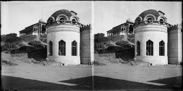 Edifici en construcció amb un home treballant i al fons el pavelló de la Reina al Tibidabo