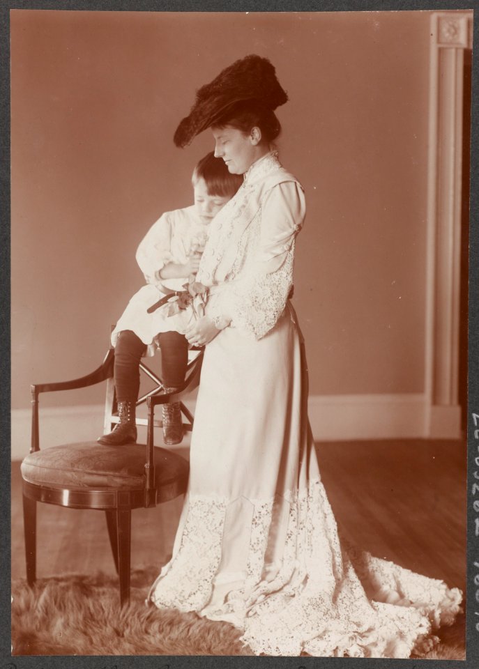 Edith Kermit Carow Roosevelt, full-length portrait, standing, facing left, with arm around young Quentin Roosevelt, who is seated on back of chair LCCN89709272