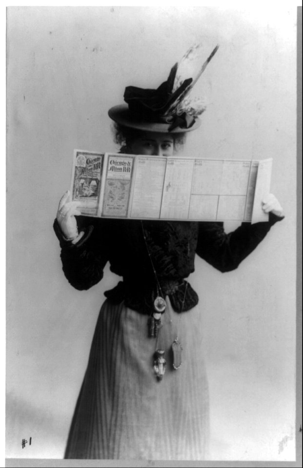 Edna Wallace Hopper, three-quarter length portrait, standing, facing right, looking over schedule for Chicago & Alton Railroad LCCN91481439