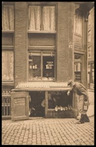 Een schoenmaker in een pothuis in de Nes 87 bij de Langebrugsteeg. Uitgave N.V. A.J. Nuss, amsterdam, Afb PBKD00332000004