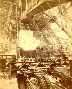 Eiffel Tower machinery with man beside wheel that raises elevator, during Paris Exposition