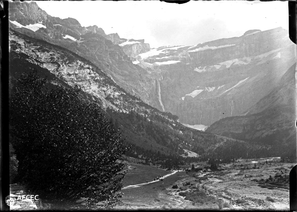 El circ de Gavarnia amb una cascada i muntanyes nevades al fons, a baix un camí amb gent