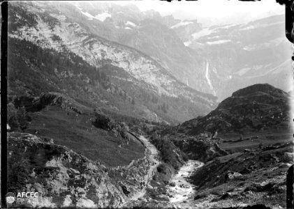 El circ de Gavarnia amb una cascada i muntanyes nevades al fons, en primer terme un camí i un riu