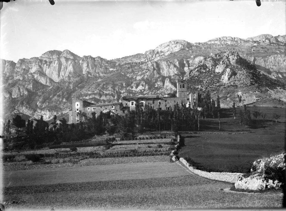 El monestir de San Victorián voltat d'arbres i camps, al fons muntanyes