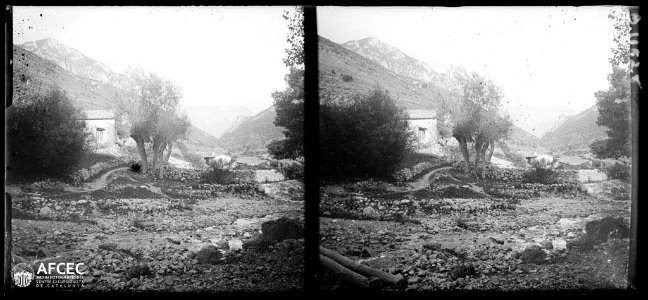 El molí de Fórnols amb un riu en primer terme i muntanyes al fons