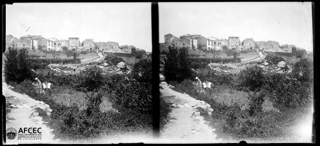 El poble de la Vajol des dels afores amb una persona a la vora del camí en primer terme