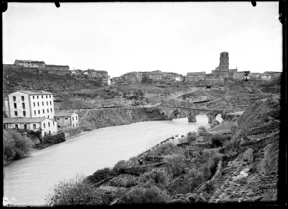 El poble de Pertusa amb el riu Alcandra i un pont en primer terme