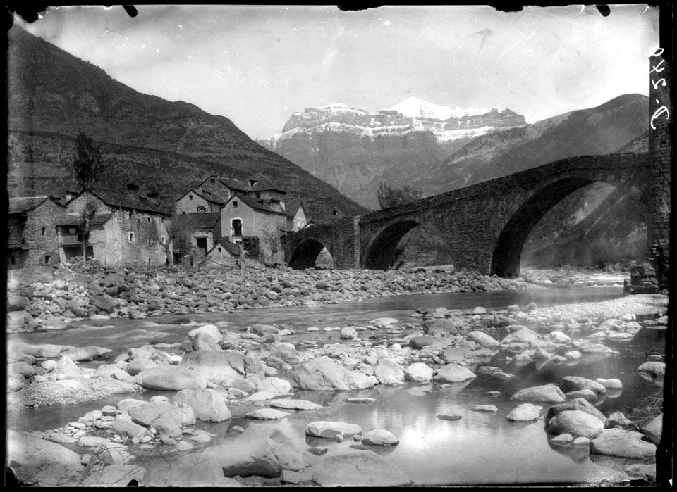 El poble de Broto amb un pont sobre el riu Ara en primer terme i muntanyes al fons