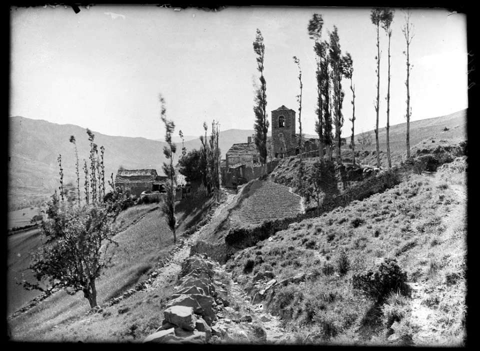 El poble de Serrate amb un camí, un camp i arbres en primer terme