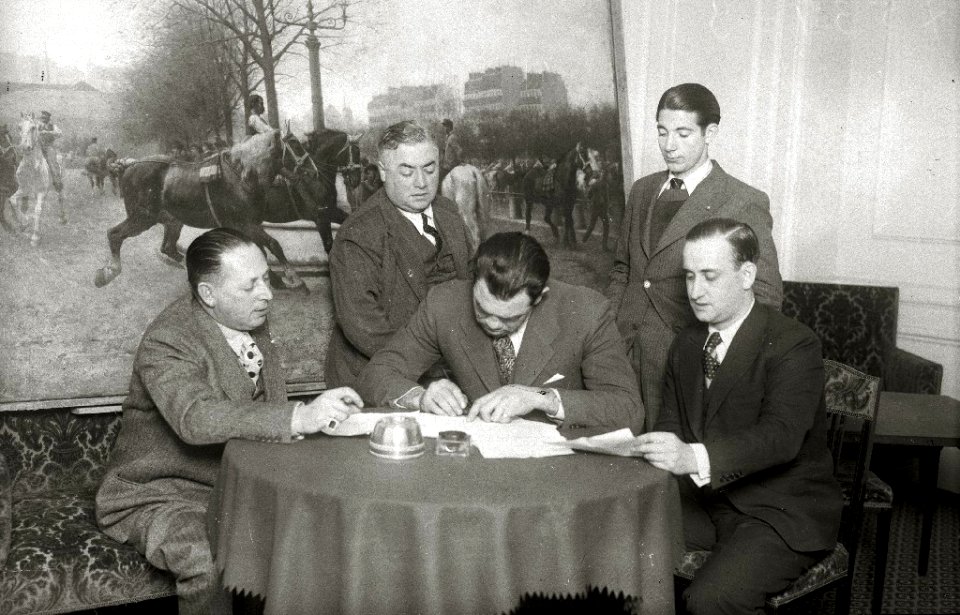 El púgil Paulino Uzcudun firmando unos documentos en un salón (1 de 1) - Fondo Car-Kutxa Fototeka