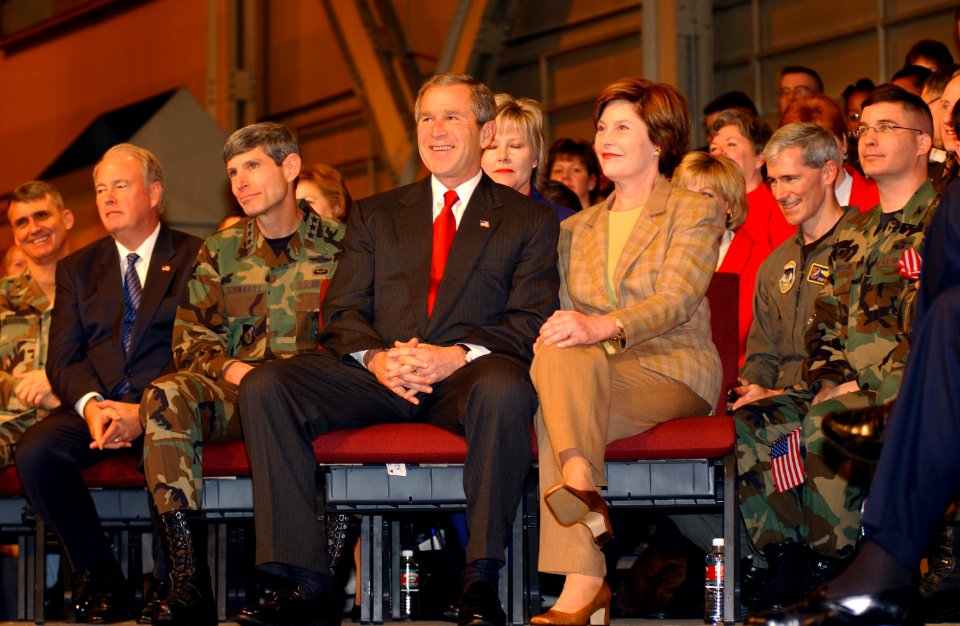 George W. Bush and Laura Bush sit together on the stage before a full house in Hangar 3 at Elmendorf Air Force Base, Alaska