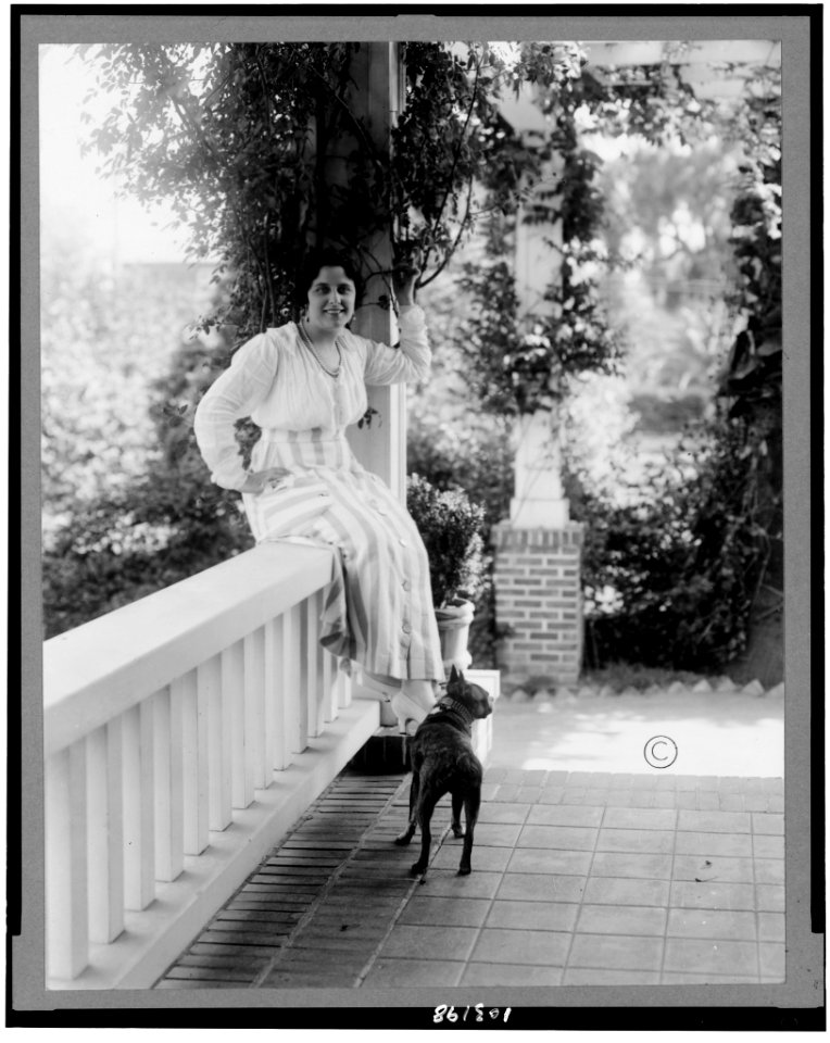 Geraldine Farrar, full-length portrait, seated on porch banister, facing slightly right; dog on porch) - Hartsook Photo, S.F.-L.A LCCN91784354