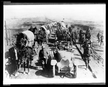 German officers in an automobile on the road with a convoy of wagons; soldiers walk along side the road LCCN2005697185 photo