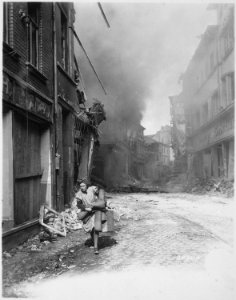 German woman carrying a few possessions runs from burning building in Siegburg, Germany. Fire started by Nazi saboteur. - NARA - 540137