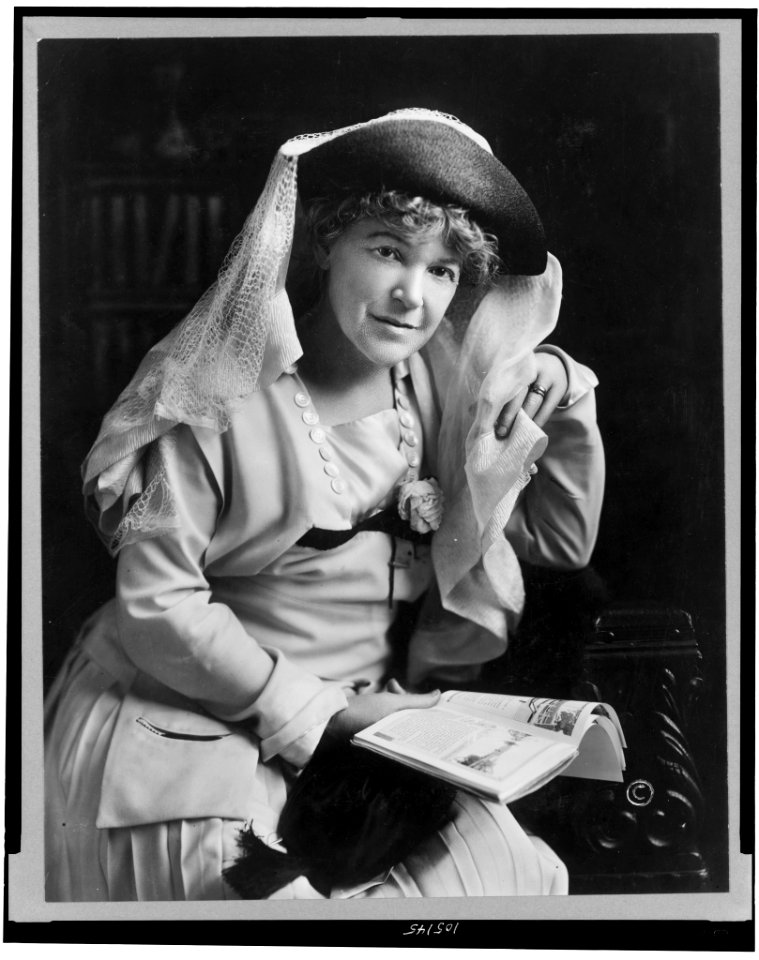 Ella Wheeler Wilcox, seated, three-quarter length portrait, wearing veiled hat and holding book, facing slightly right LCCN92522148