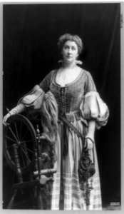 Emma Eames, three-quarter length portrait, standing, facing front with right hand on spinning wheel LCCN91481435