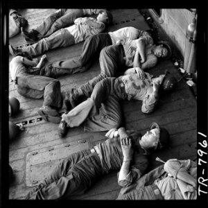 Enlisted men, exhausted after more than 24 hours at general quarters, sleep in tangled patterns aboard the USS... - NARA - 520905