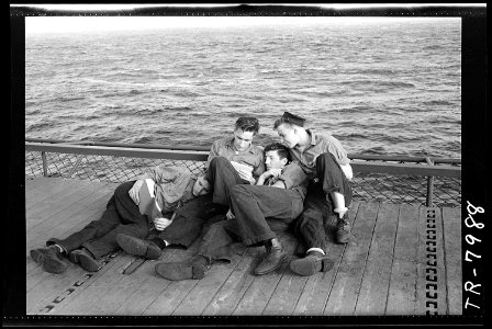 Enlisted men reading on edge of elevator aboard USS Lexington (CV-16). - NARA - 520895