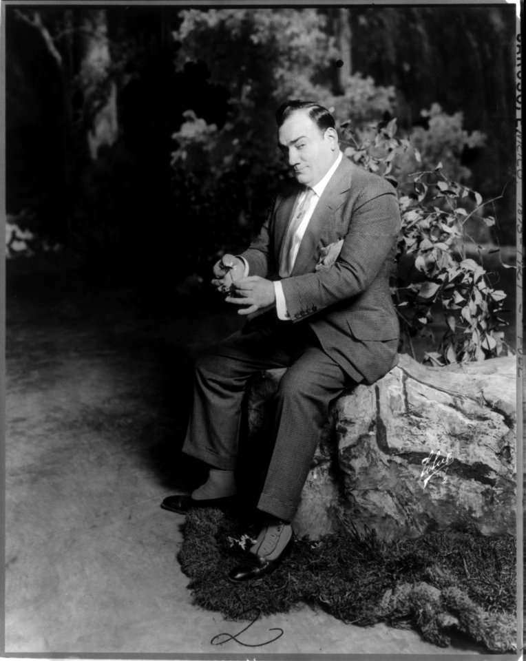 Enrico Caruso, 1873-1921, full-length portrait, seated, facing left, holding flower LCCN2005680260
