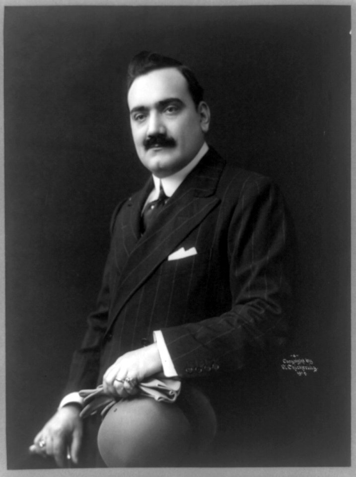 Enrico Caruso, half-length portrait, seated, facing left, holding hat, walking stick, and gloves LCCN89714526