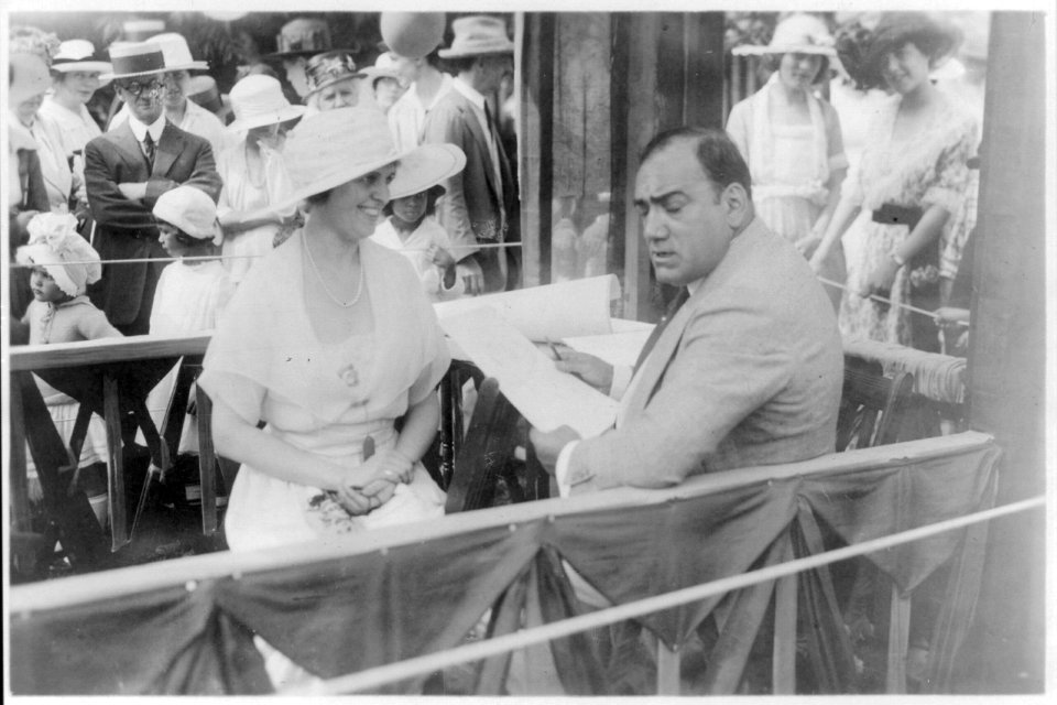 Enrico Caruso, 1873-1921, drawing caricature sketches in booth at charity fair in Southampton, L.I., with sitter, Mrs. Albert Gallatin LCCN2005680291