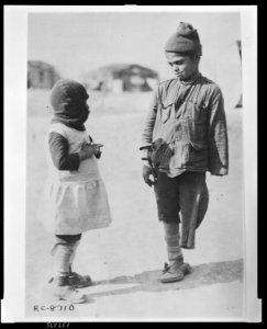 Exchanging news - two of the smaller members of the Greek colony which has been set up for repatriates from the Caucasus outside Salonica The boy lost one of his arms and legs in a railway LCCN2010648496
