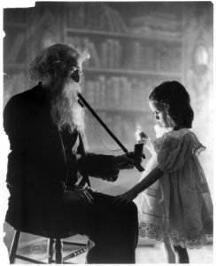 Girl lighting long pipe of old bearded man LCCN2003675175