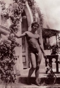Gloeden, Wilhelm von (1856-1931) - n. 0692 - Vor einem Haus posierender Junge mit Stab und Blumenkrone (Zeno Fotografie)