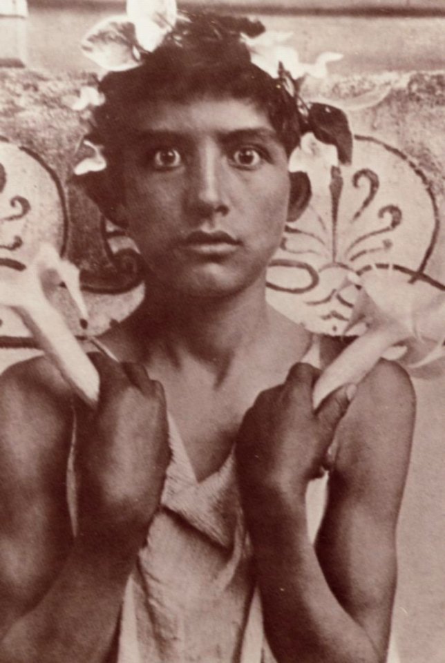 Gloeden, Wilhelm von - Mit Blüten gekrönter Junge, zwei Blütenkelche haltend (Zeno Fotografie)