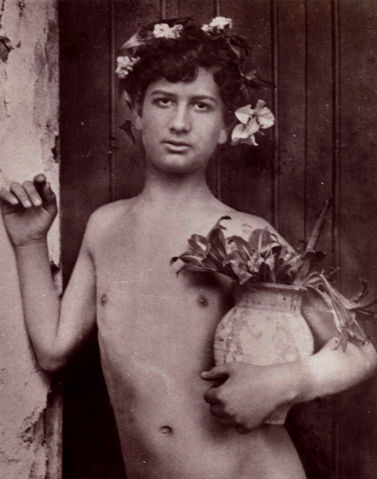 Gloeden, Wilhelm von - Mit Blüten bekränzter Knabe, eine Vase mit Lilien haltend (Zeno Fotografie)