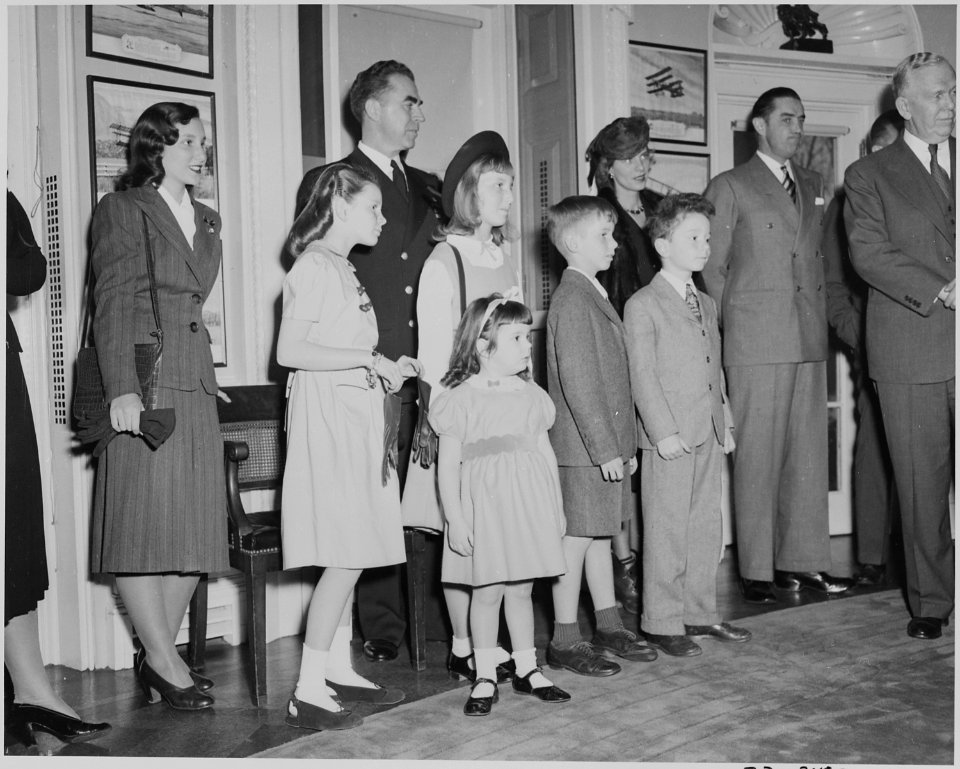Family members of W. John Kennedy and John L. Sullivan, the Undersecretary and Secretary of the Navy, watch the oval... - NARA - 199637