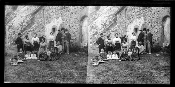 Façana d'una masia amb un grup familiar i un sacerdot